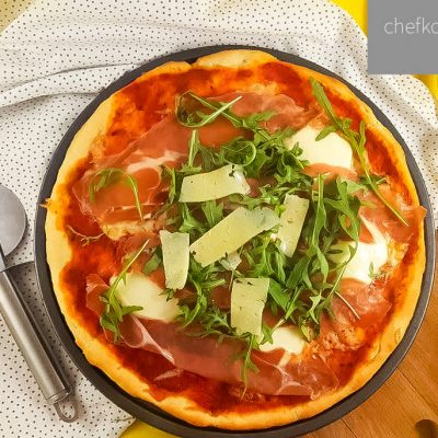 Pizza mit Rucola, Parmesan und Parmaschinken